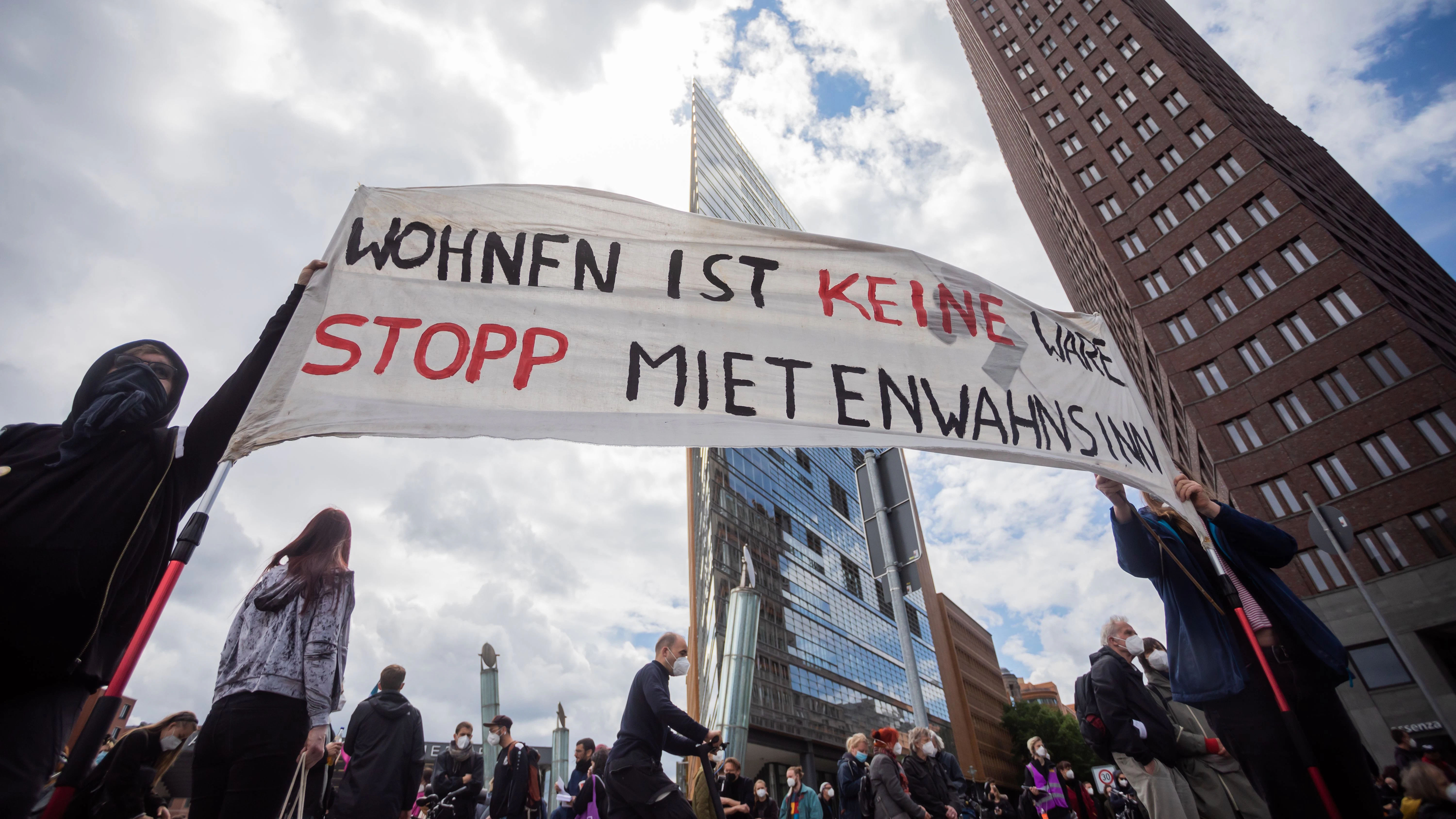 Potsdamer Platz: Teilnehmer der Mietendemo halten ein Banner mit der Aufschrift „Wohnen ist keine Ware, stopp Mietenwahnsinn“.