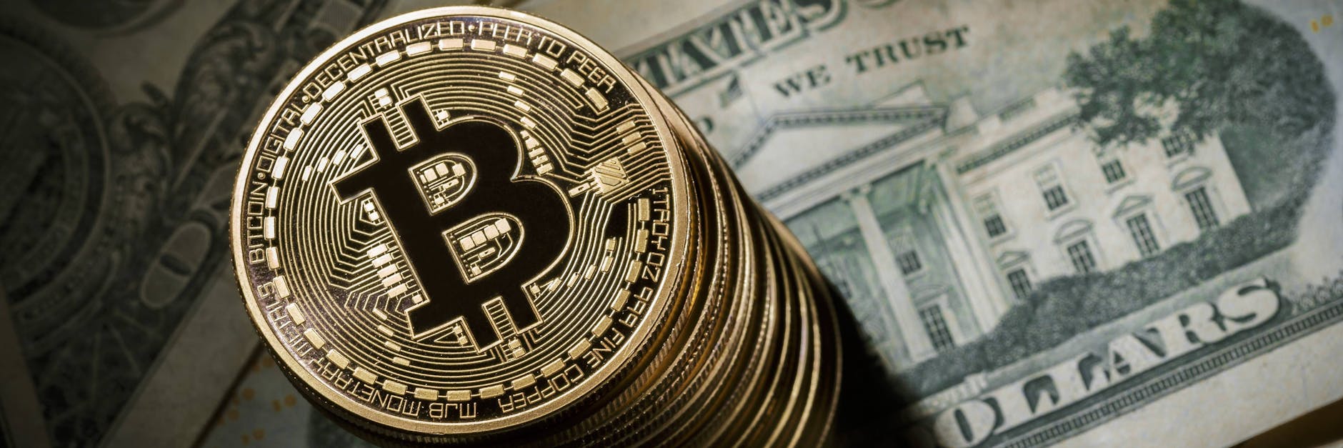 Ein Stapel Bitcoin-Münzen liegt auf Dollarscheinen (Symbolfoto)