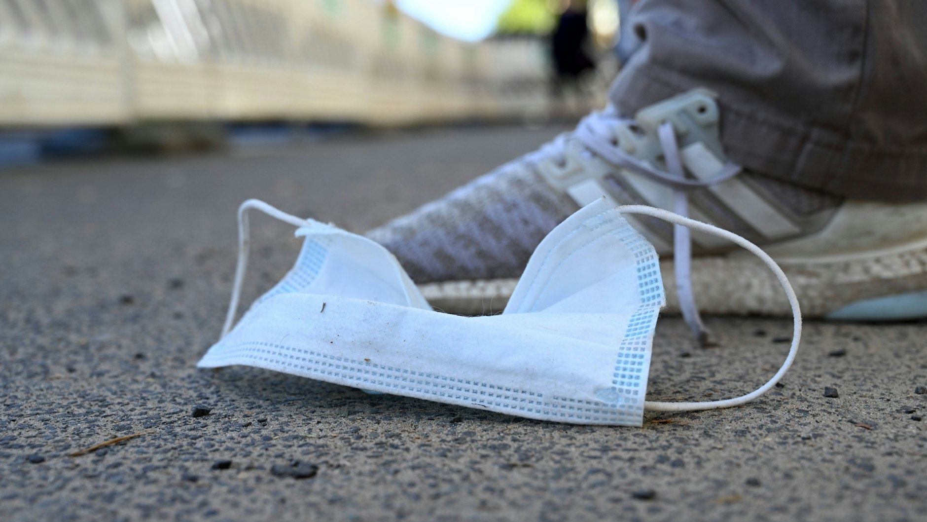 Eine weggeworfene Einwegmaske liegt auf dem Gehweg (Symbolbild). Sinkende Corona-Fallzahlen werfen die Frage auf: Ist die Pandemie vorbei?