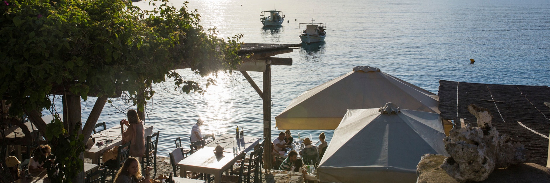 Touristen sitzen in einem Café am Meer in Limeni, einem kleinen Fischerhafen auf der Halbinsel Mani.&nbsp;
