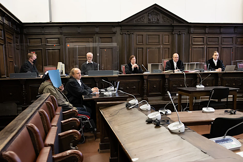 Der Angeklagte verdeckt in diesem Bild vom Prozessbeginn im November sein Gesicht.