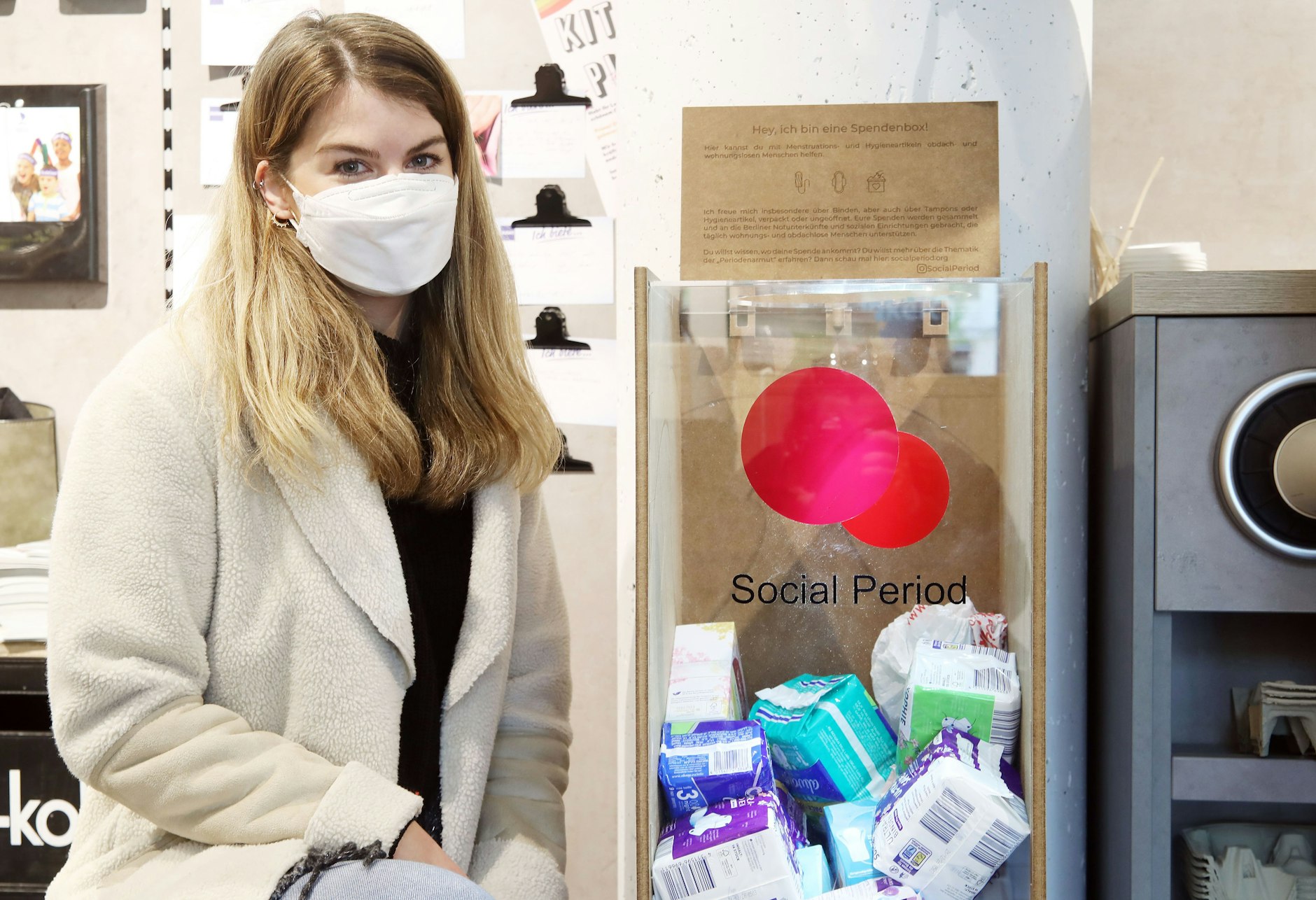 Roksana Witusinski von Social Period neben einer Spendenbox für Menstruationsprodukte.