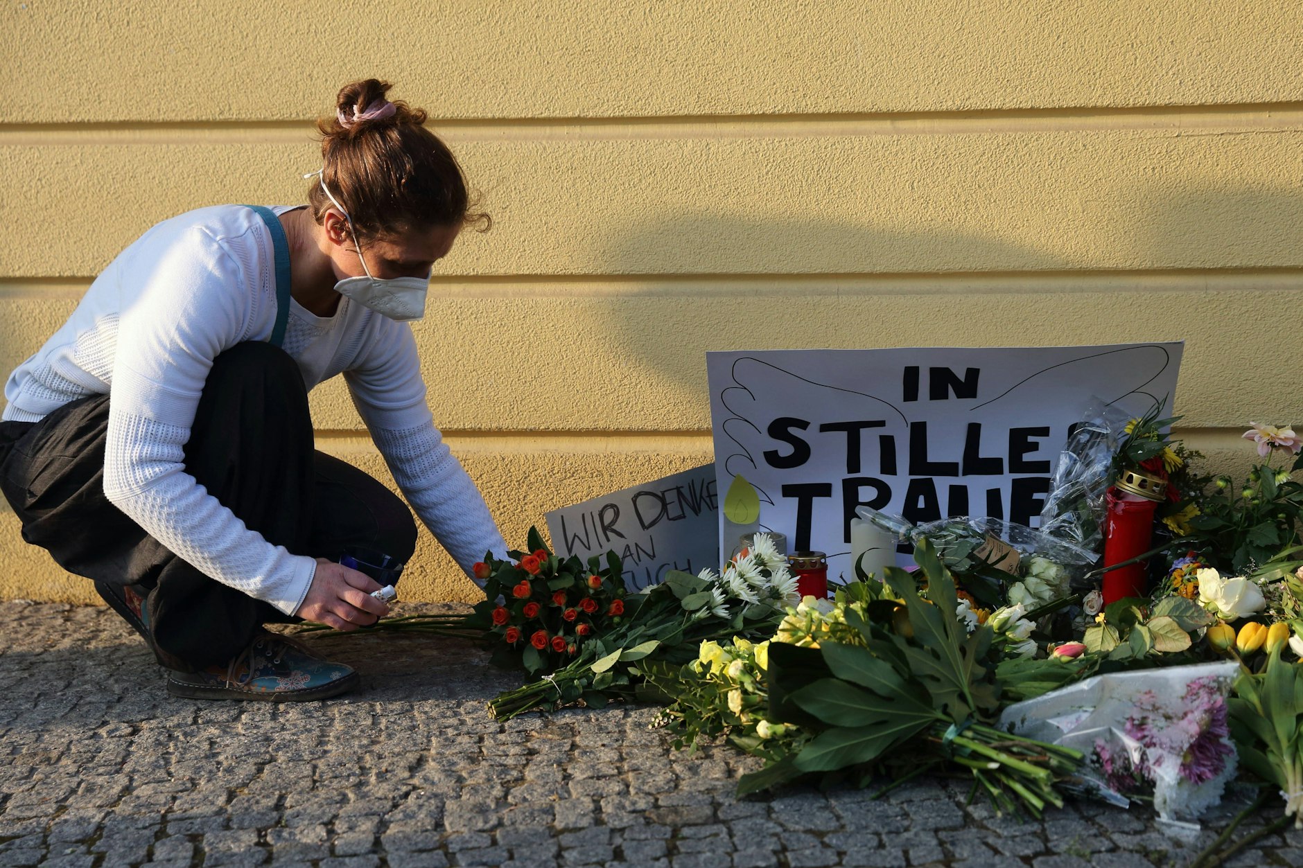 Eine Frau legt Blumen nieder und gedenkt der Opfer am Babelsberger Oberlinhaus in Potsdam.
