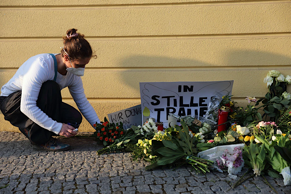 Eine Frau legt Blumen nieder und gedenkt der Opfer am Babelsberger Oberlinhaus in Potsdam.