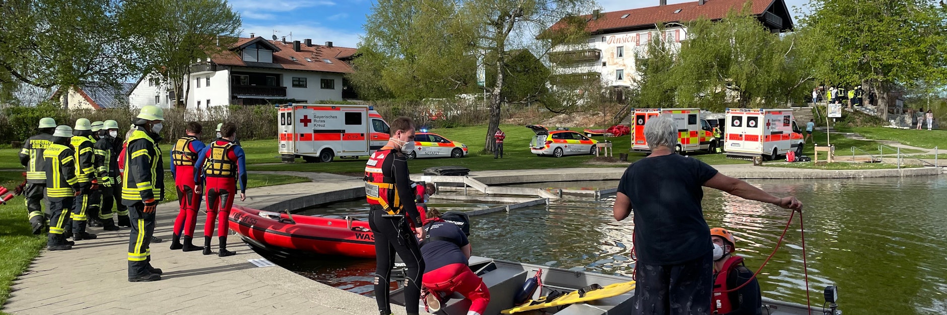 Einsatzkräfte der Feuerwehr und Rettungsdienste stehen an einem Badesee bei Sulzberg im Oberallgäu. Ein Kleinflugzeug mit vier Menschen an Bord ist kurz nach dem Start in den See gestürzt.