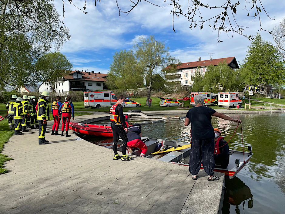 Einsatzkräfte der Feuerwehr und Rettungsdienste stehen an einem Badesee bei Sulzberg im Oberallgäu. Ein Kleinflugzeug mit vier Menschen an Bord ist kurz nach dem Start in den See gestürzt.