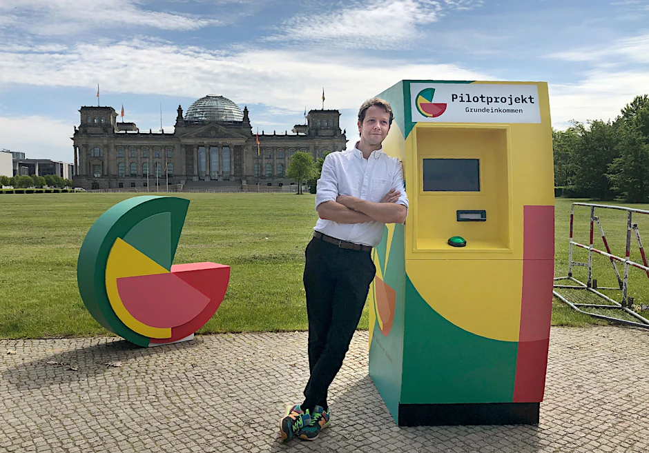 Michael Blohmeyer, Initiator des Vereins „Mein Grundeinkommen“, steht an einem symbolischen Geldautomaten.