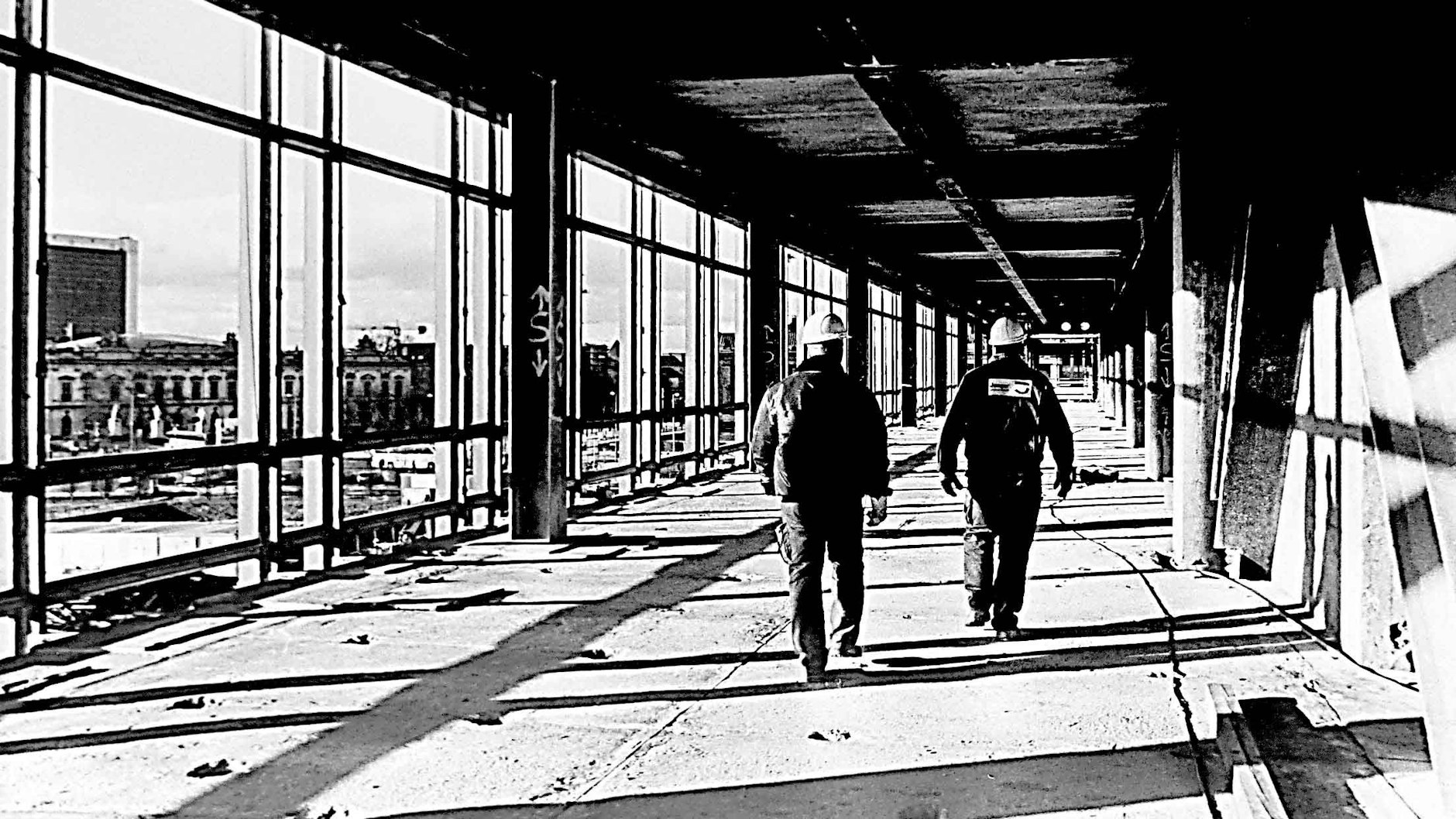 Bauarbeiter gehen durch die entkernte und abrissbereite Ruine, der Blick nach draußen geht zum Zeughaus. Der Palast war der erste freitragende <a href="https://de.wikipedia.org/wiki/Stahlskelettbau">Stahlskelettbau</a> in der DDR.