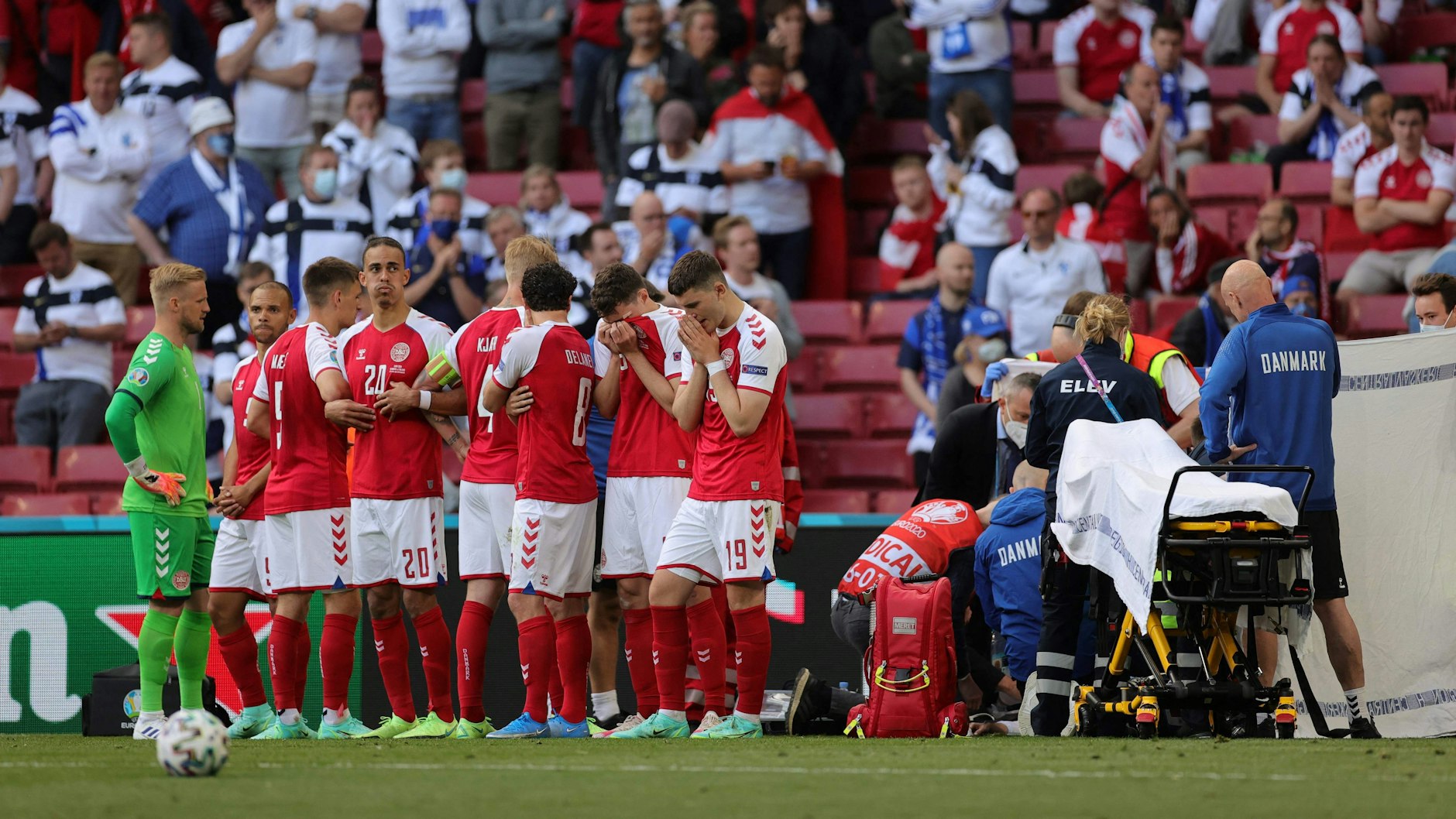 Die dänischen Spieler stehen um ihren am Boden liegenden Mitspieler Christian Eriksen.
