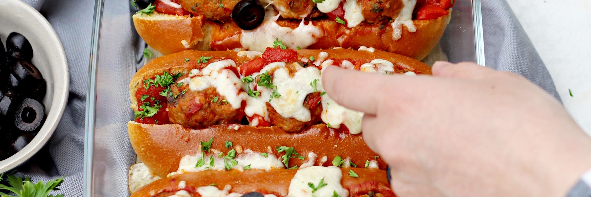 Bevor die Meatball-Sandwiches im Ofen für 10 Minuten mit Mozzarella überbacken werden, kommen in jedes Briochebrötchen&nbsp; Hackbällchen und etwas Soße.&nbsp;