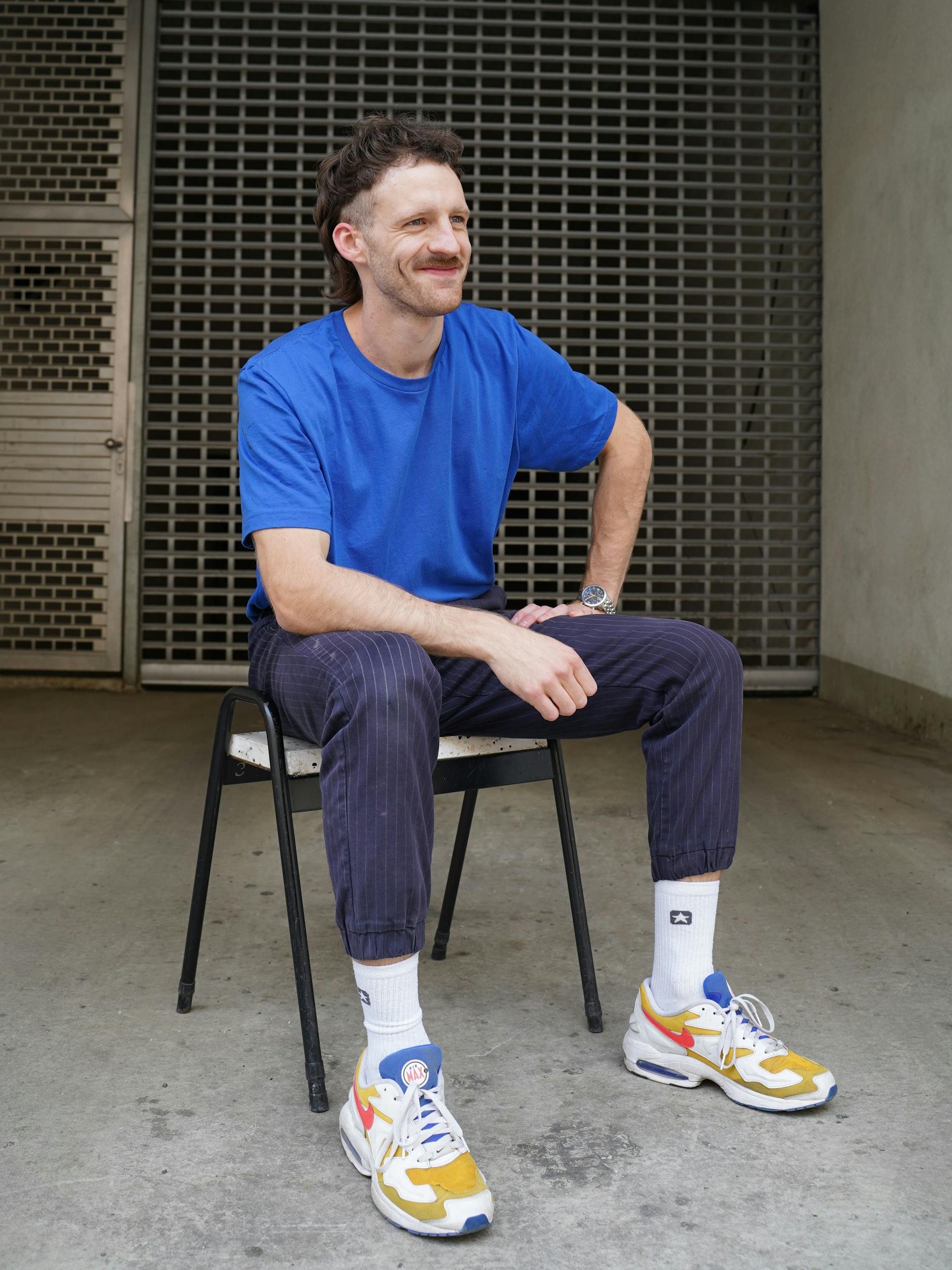 Enzo arbeitet im Café Five Elephant. Er posiert für uns in einer Hose von Uniqlo, Converse-Tennissocken und Nike Airmax. 