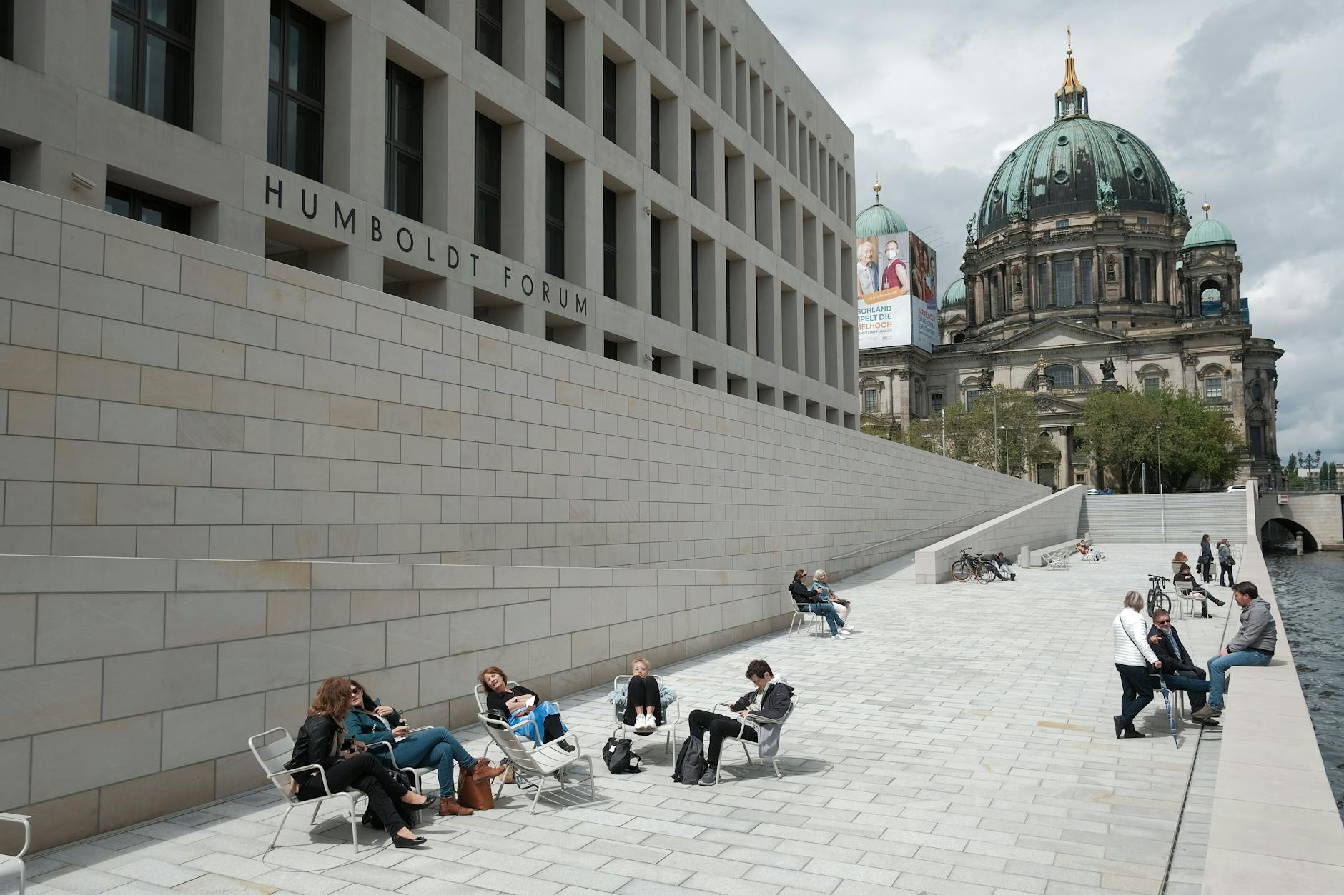 Besucher sitzen vor dem Humboldt Forum, das am 20. Juli wieder für alle Gäste öffnet.