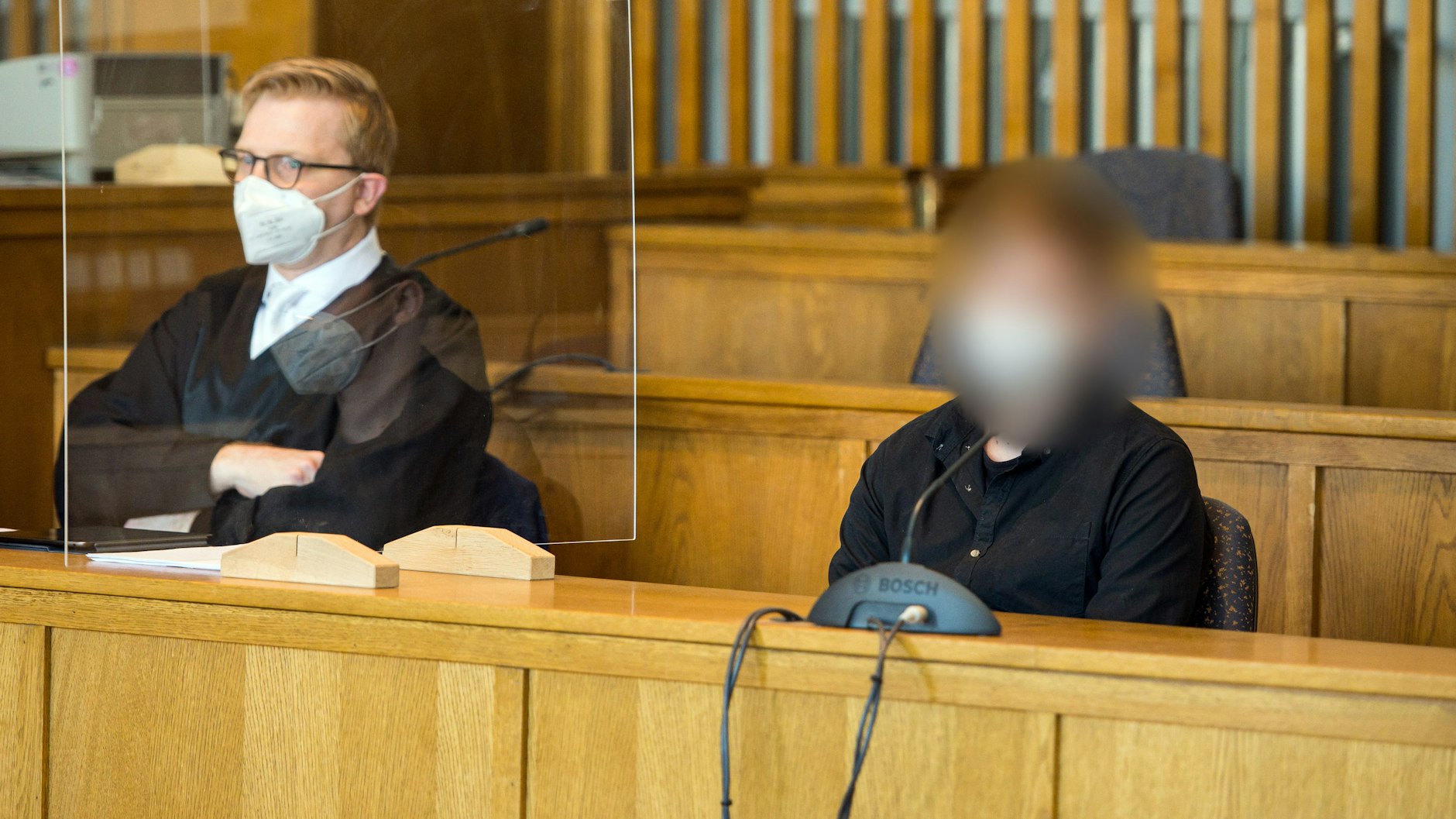 Der Angeklagte sitzt im Gerichtssaal des Landgerichts Saarbrücken neben seinem Anwalt.