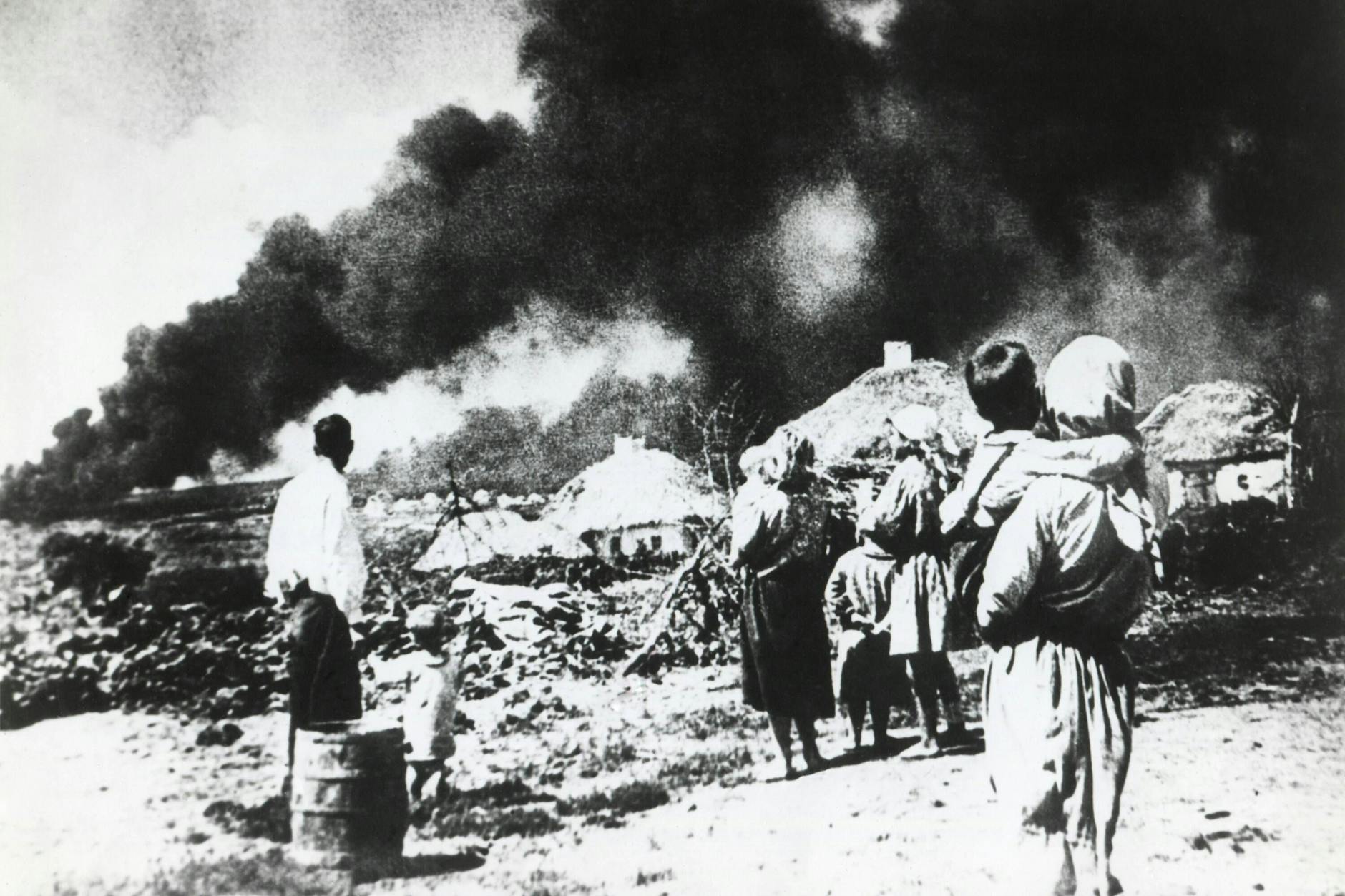 Eine Familie schaut in der Sowjetunion 1941 zu, wie deutsche Truppen sich nähern und auf ihre Häuser schießen.