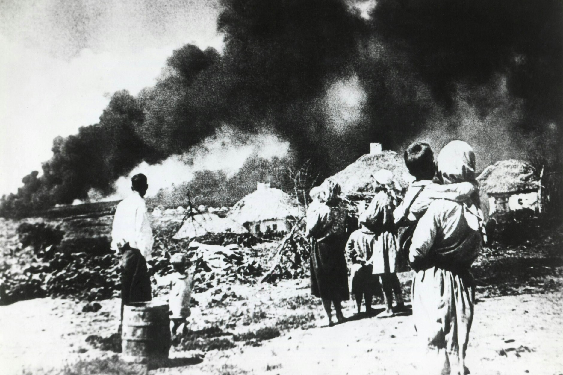 Eine Familie schaut in der Sowjetunion 1941 zu, wie deutsche Truppen sich nähern und auf ihre Häuser schießen.