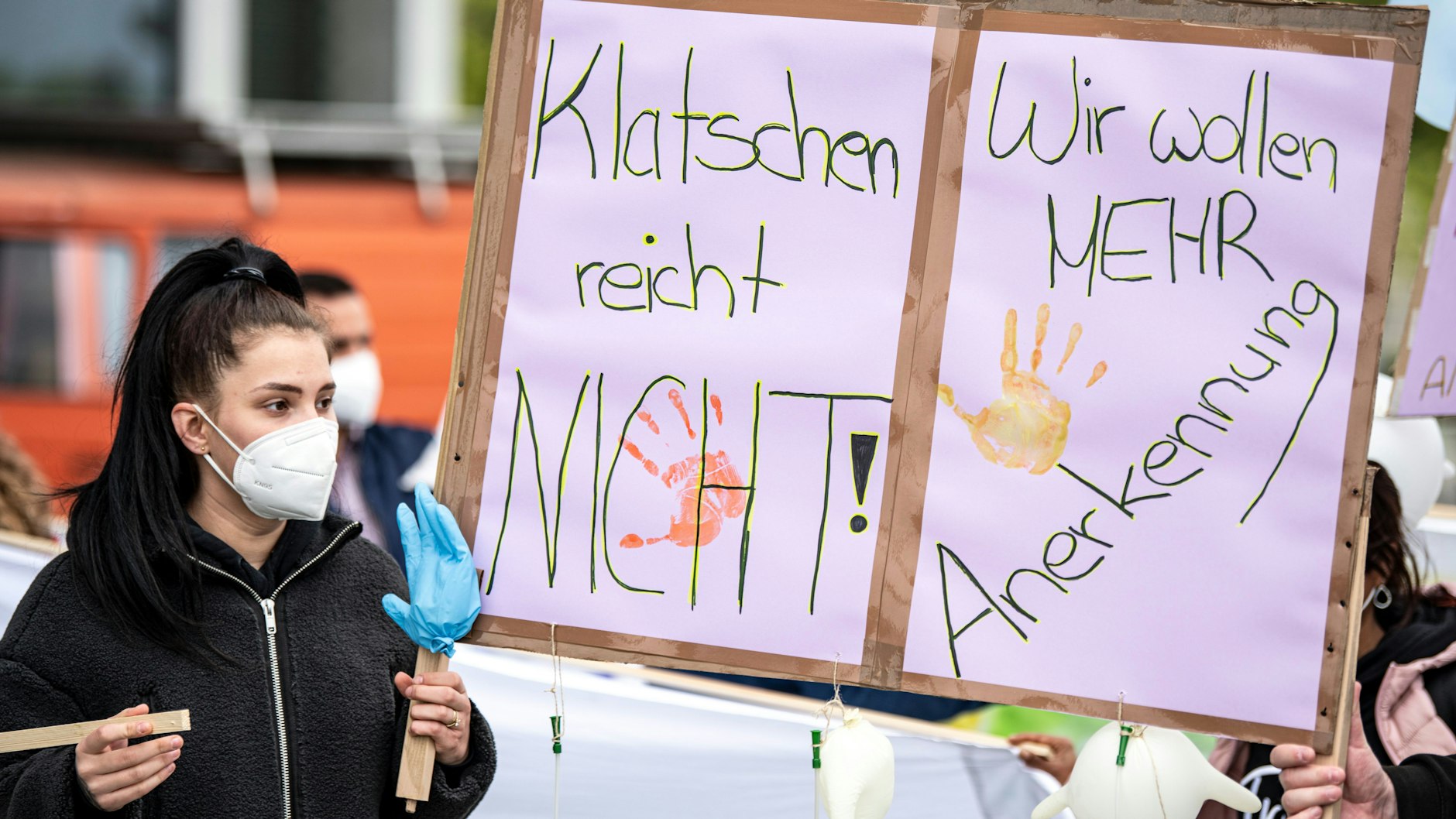 Eine Frau hält bei der Aktion „Der Pflege geht die Luft aus“ ein Plakat mit der Aufschrift „Klatschen reicht nicht“ hoch.&nbsp;