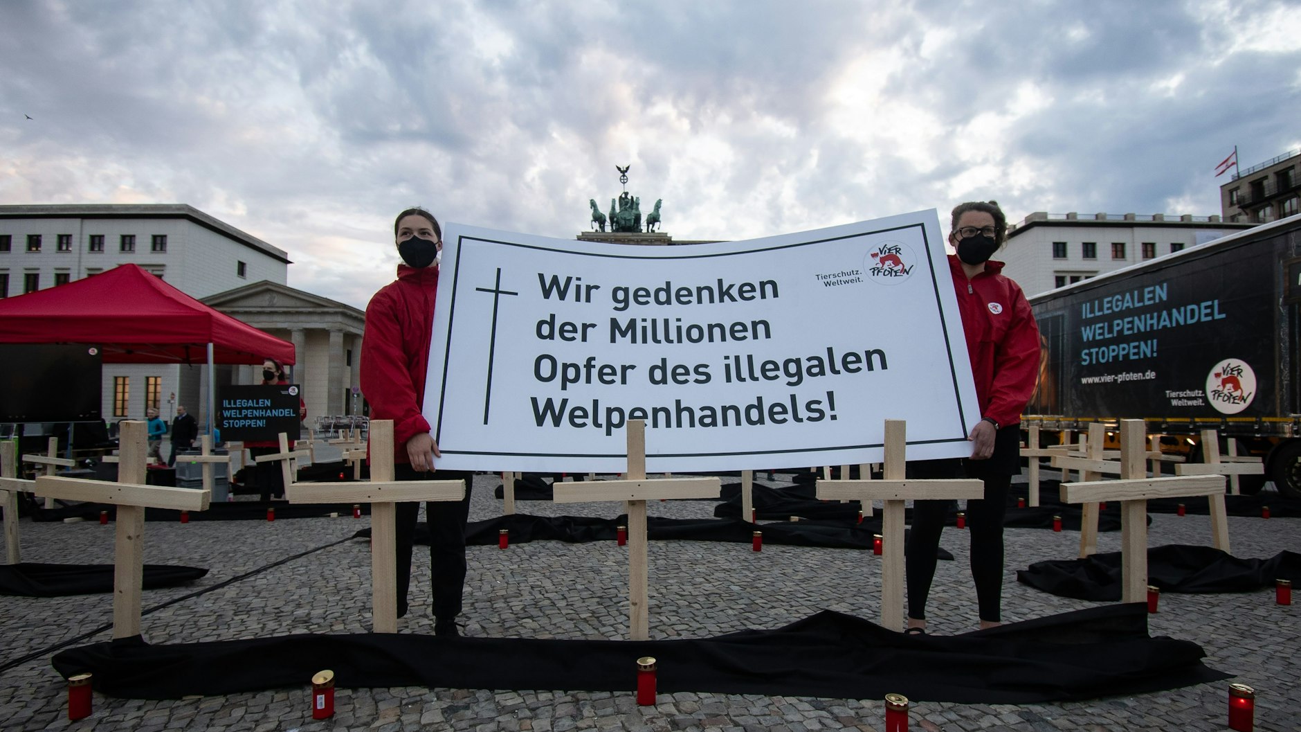 Aktivisten der Stiftung für Tierschutz „Vier Pfoten“ halten ein Schild mit dem Aufdruck „Wir gedenken der Millionen Opfer des illegalen Welpenhandels“ auf dem Pariser Platz.