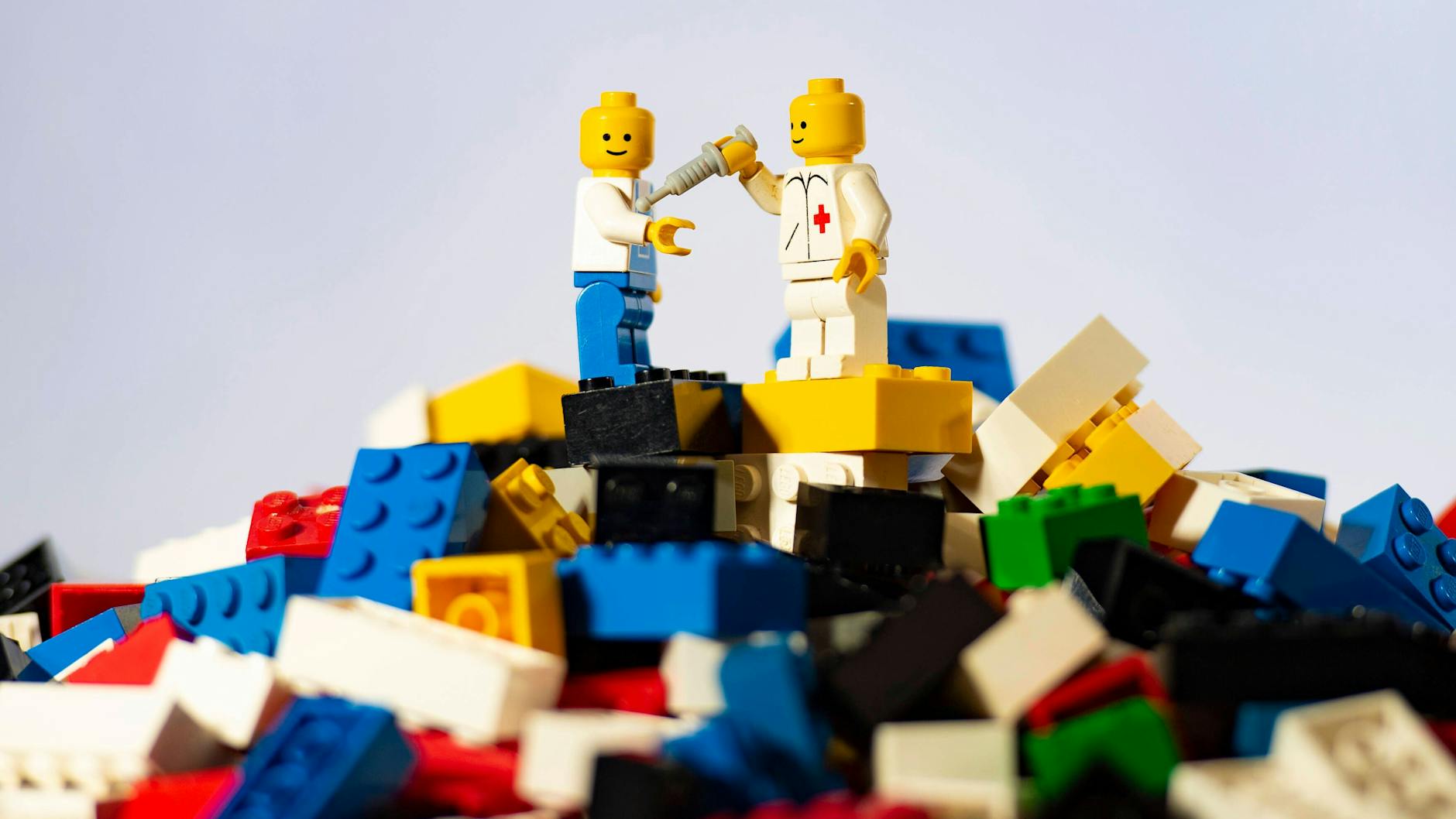 Arbeiter und Arzt auf einem Berg von Legosteinen.