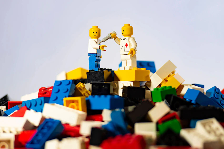 Arbeiter und Arzt auf einem Berg von Legosteinen.