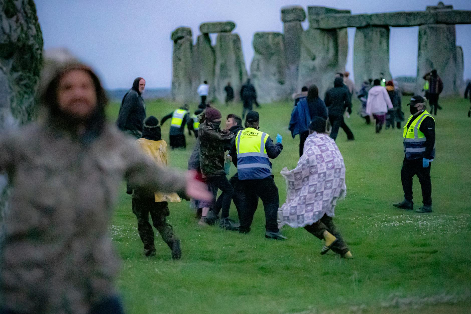 Menschen bahnen sich ihren Weg an Sicherheitspersonal vorbei in Richtung Stonehenge.