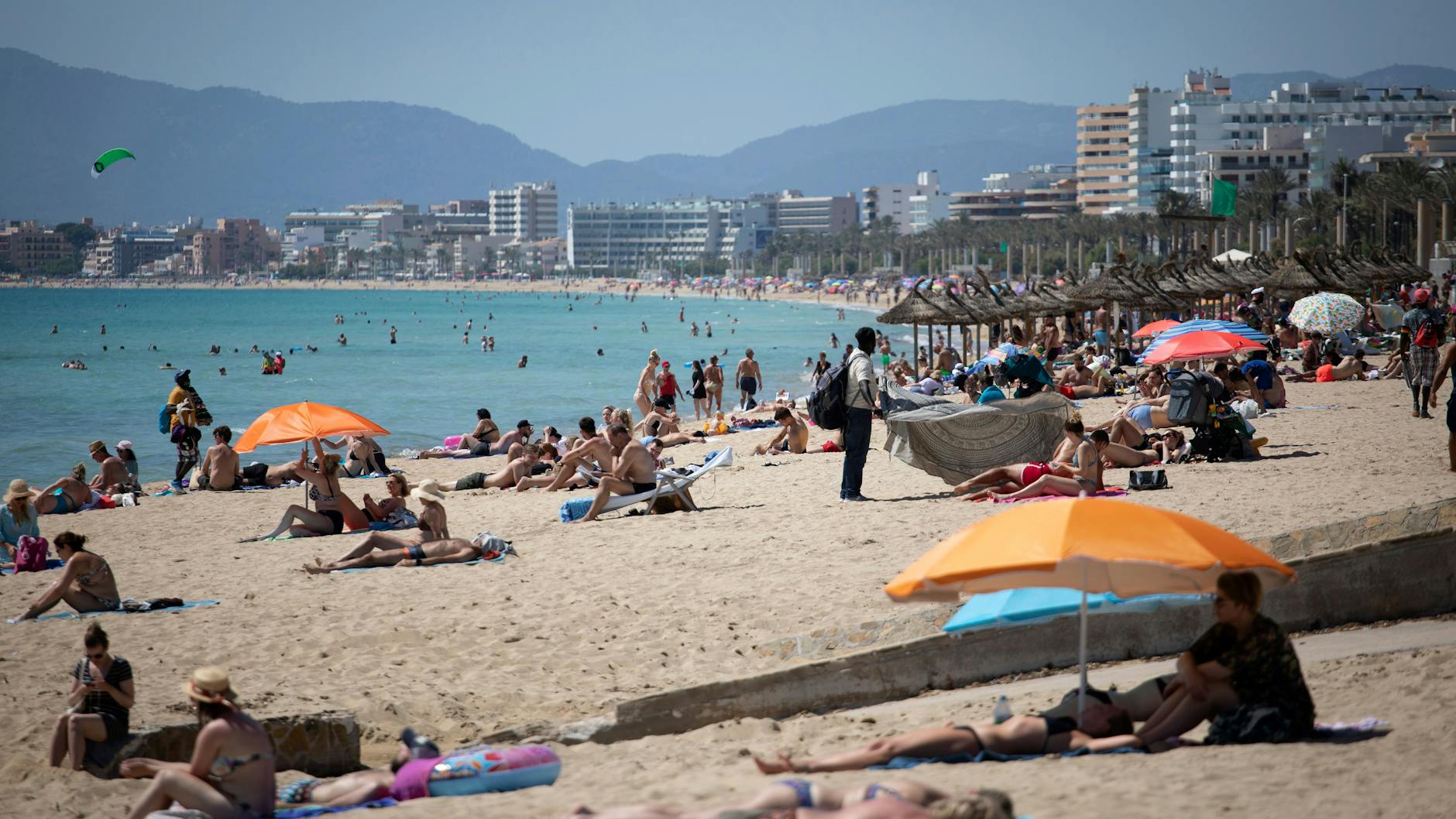 Touristen genießen die Sonne an einem Strand auf Mallorca. Bei Klassenfahrten auf die Insel haben sich mehrere Hundert Schüler mit Corona infiziert.