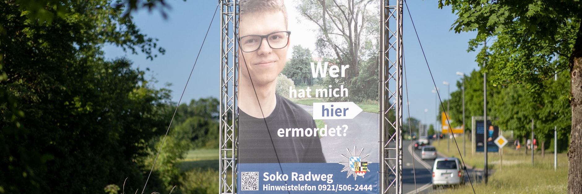 „Wer hat mich hier ermordet?“ steht auf einem großen Plakat mit Foto des Opfers neben dem Tatort.