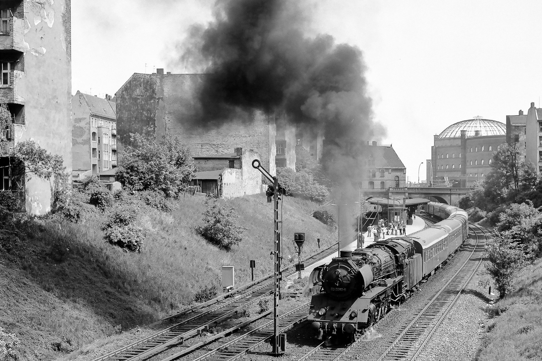 Als die Fernverkehrszüge auf dem Ring noch mit Dampf fuhren: Im August 1979 passiert ein Schnellzug nach Stralsund den S-Bahnhof Prenzlauer Allee. Im Hintergrund ist einer der Gasometer des Gaswerks Dimitroffstraße (Danziger Straße) zu sehen. Er wurde 1984 gesprengt.&nbsp;