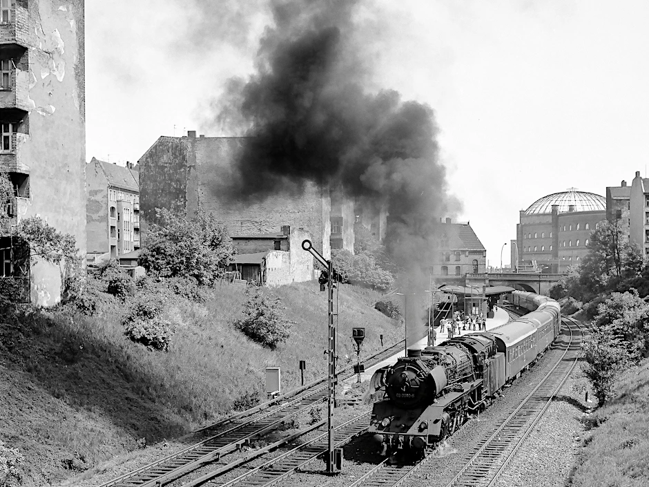 Als die Fernverkehrszüge auf dem Ring noch mit Dampf fuhren: Im August 1979 passiert ein Schnellzug nach Stralsund den S-Bahnhof Prenzlauer Allee. Im Hintergrund ist einer der Gasometer des Gaswerks Dimitroffstraße (Danziger Straße) zu sehen. Er wurde 1984 gesprengt.&nbsp;