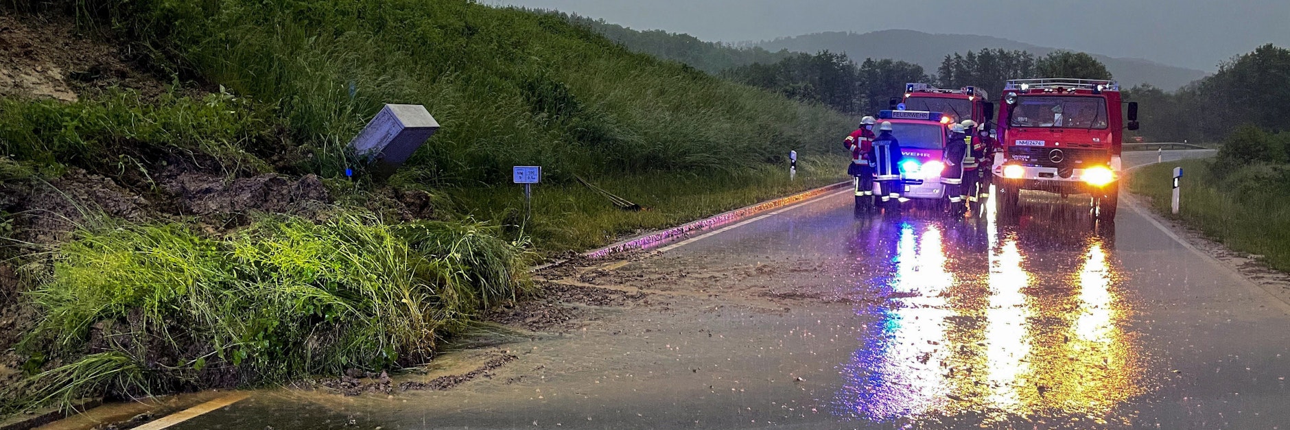 Schon seit Tagen im Dauereinsatz: Die Feuerwehr steht in Oberölsbach auf der Straße, nachdem durch Unwetter eine Böschung abgerutscht ist. 