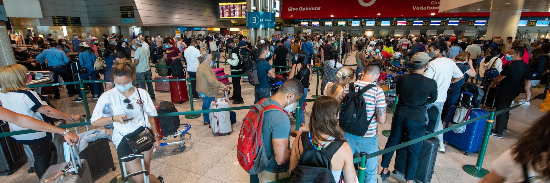 Menschen stehen Schlange am Flughafen inmitten der Corona-Pandemie, bevor neue Kontrollen für Reisende in Kraft treten.