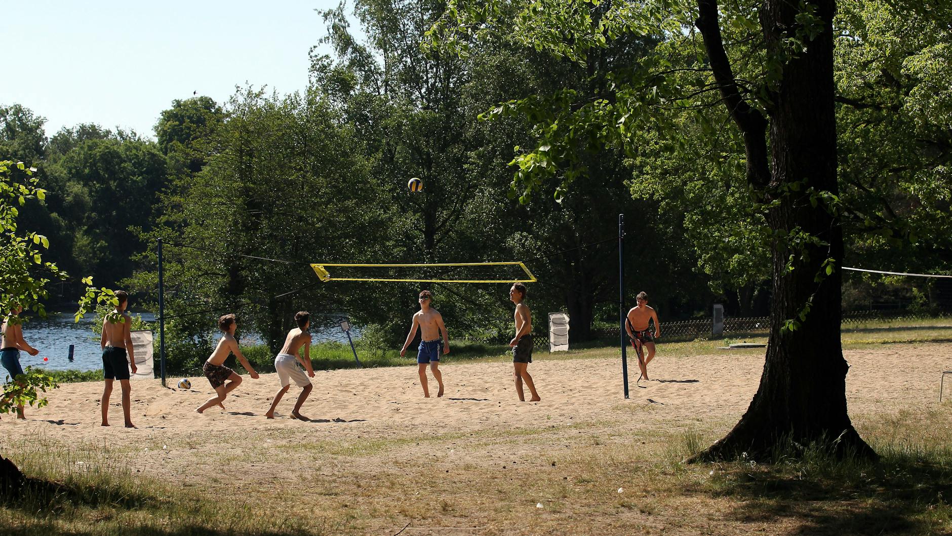 Jungs spielen am Strand Volleyball.