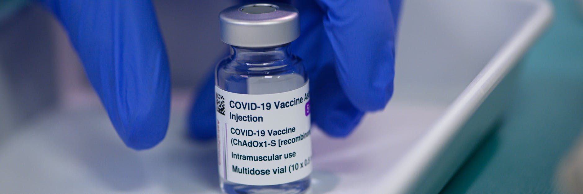 Ein Mitarbeiter im Impfzentrum in der Messe Dresden greift nach einer Ampulle des Impfstoffs Vaxzevria von Astrazeneca.