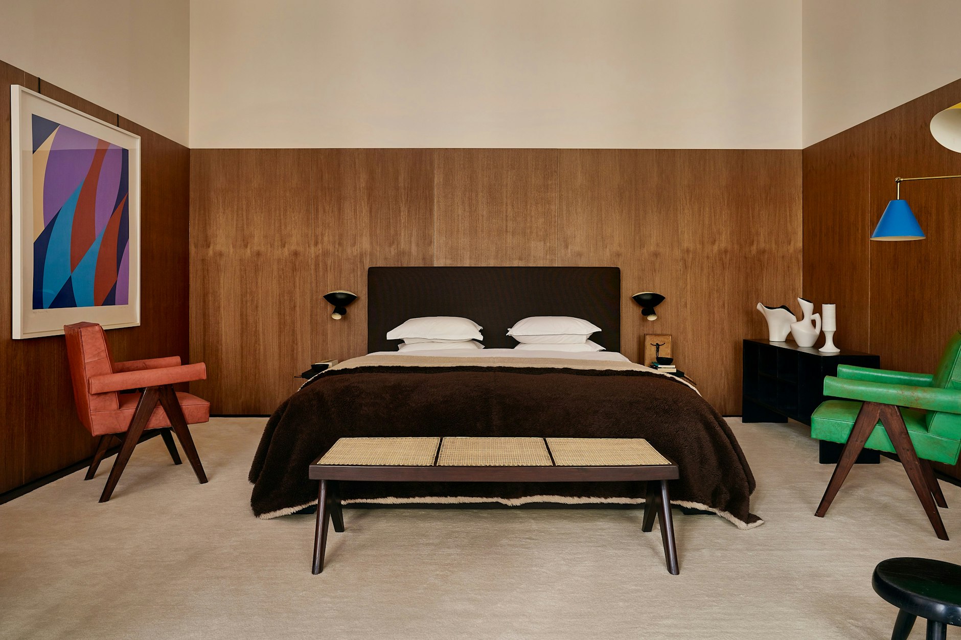 Vor der eleganten Holzvertäfelung leuchten „Senat Sessel“ von Pierre Jeanneret.