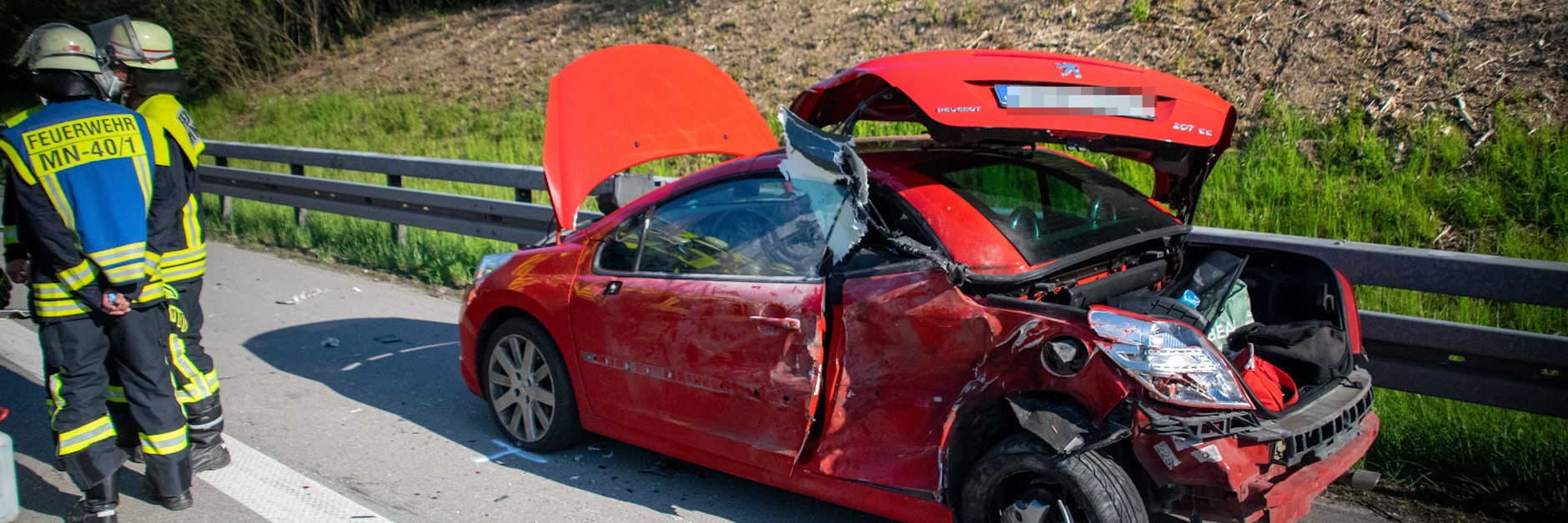 Einsatzkräfte der Feuerwehr stehen am Unfallort neben dem Autowrack.&nbsp;