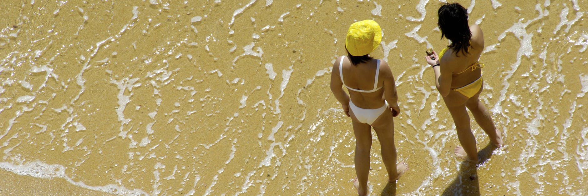 Zwei Sonnenanbeterinnen aus der Vogelperspeltive an einem Strand der Algarve in Portugal. Das Land gilt als Virusvariantengebiet, für das eine Reisewarnung in Kraft ist.