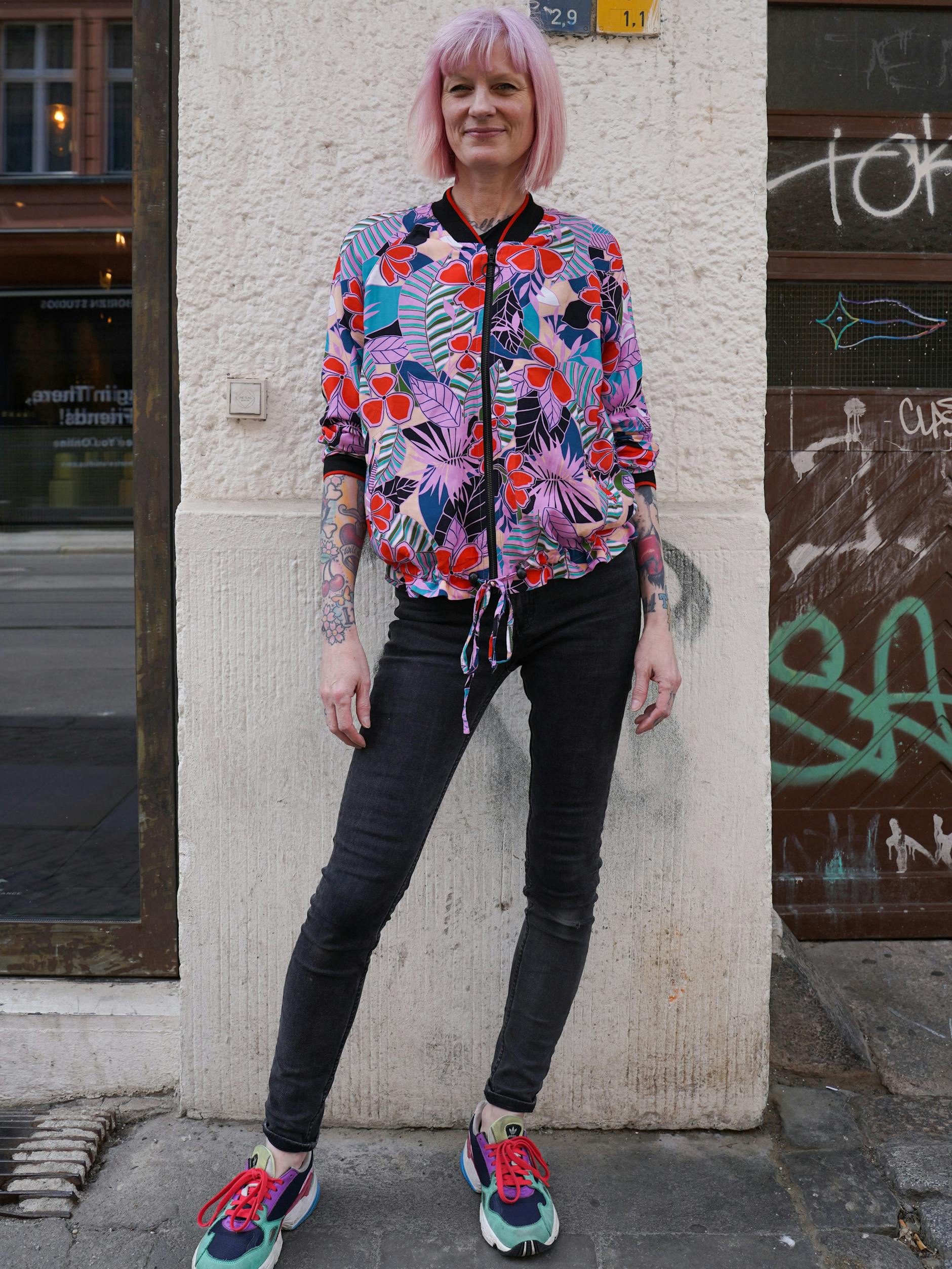 Elke betreibt seit 1997 die Boutique SOMA. Sie trägt eine Jacke der Marke Yéyé, die man bei ihr kaufen kann, dazu farblich passende Sneaker von Adidas.