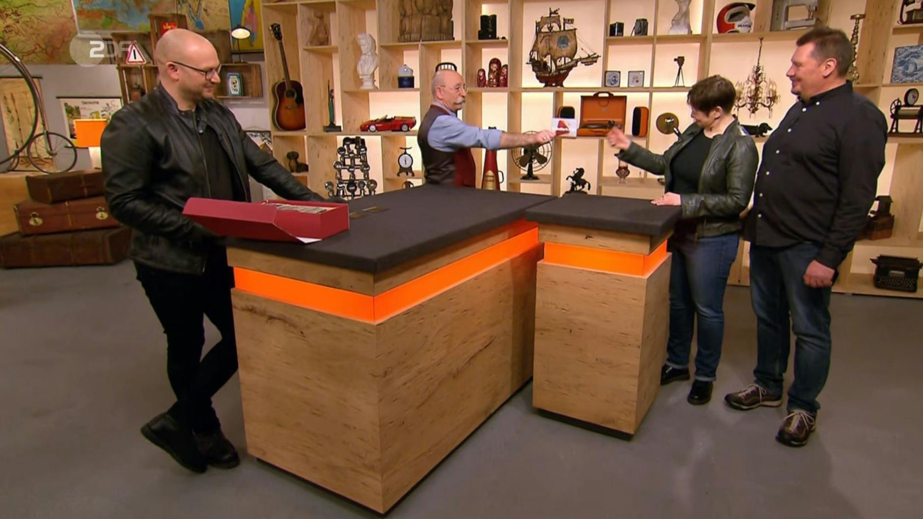 „Bares für Rares“-Moderator Horst Lichter überreicht den Kandidaten die Händlerkarte für ihre Dias.