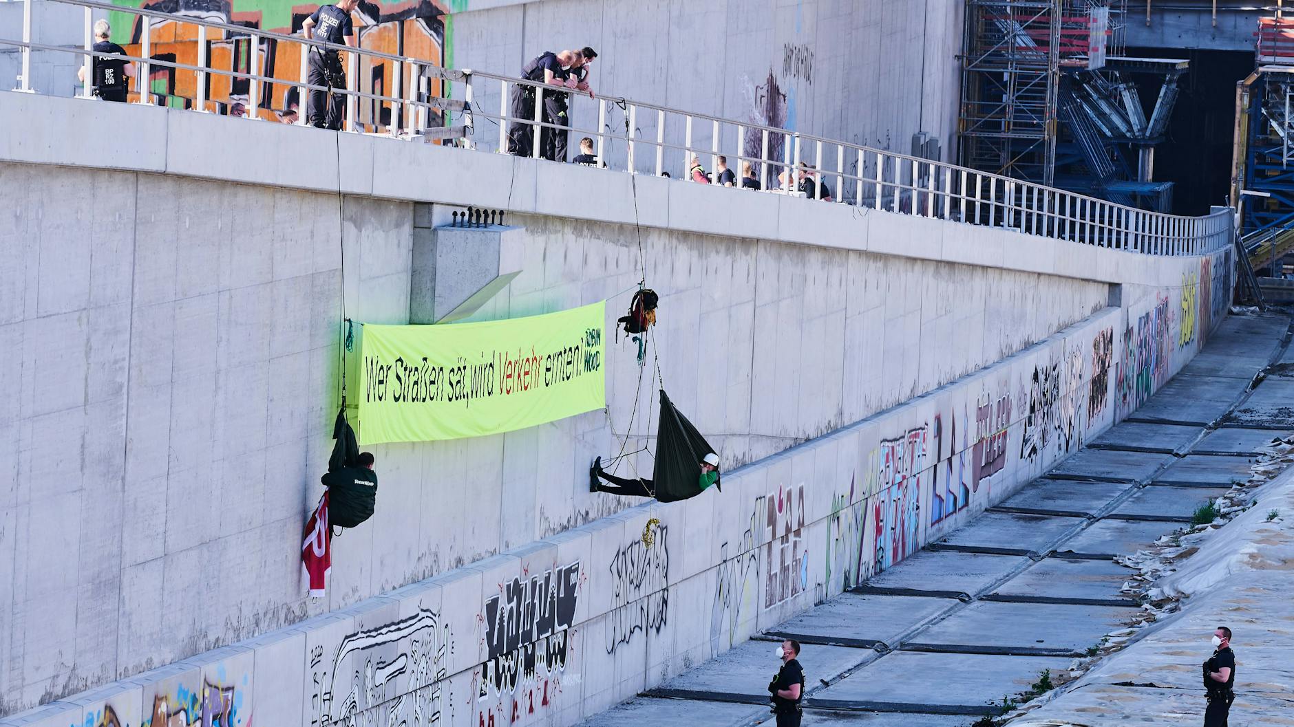 „Wer Straßen sät, wird Verkehr ernten“ steht auf dem Banner, das „Robin Wood“-Aktivisten auf dem abgesperrten Gelände an der Baustelle der Autobahn 100 an der Sonnenallee aufhängen.