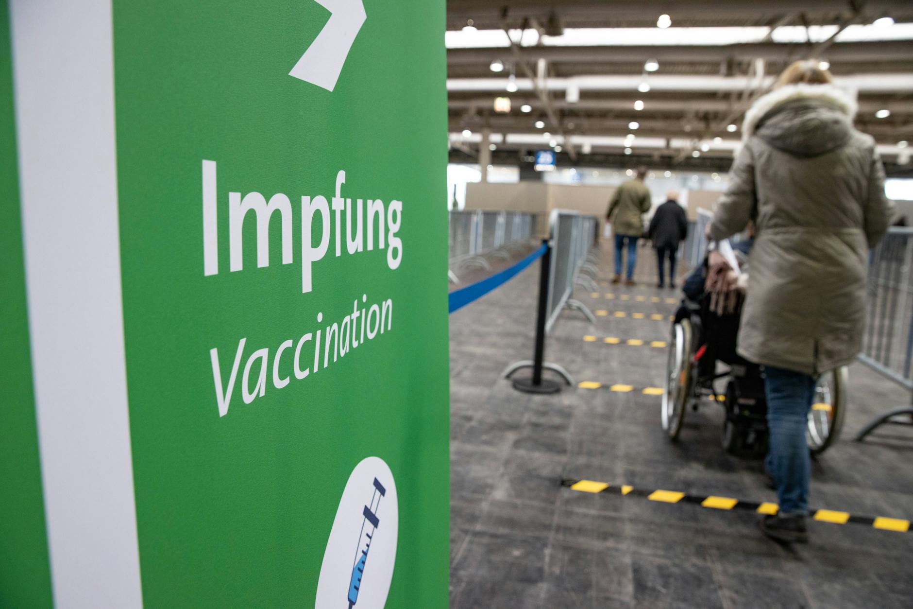 Eine Behinderte mit Helferin auf dem Weg zur Corona-Impfung