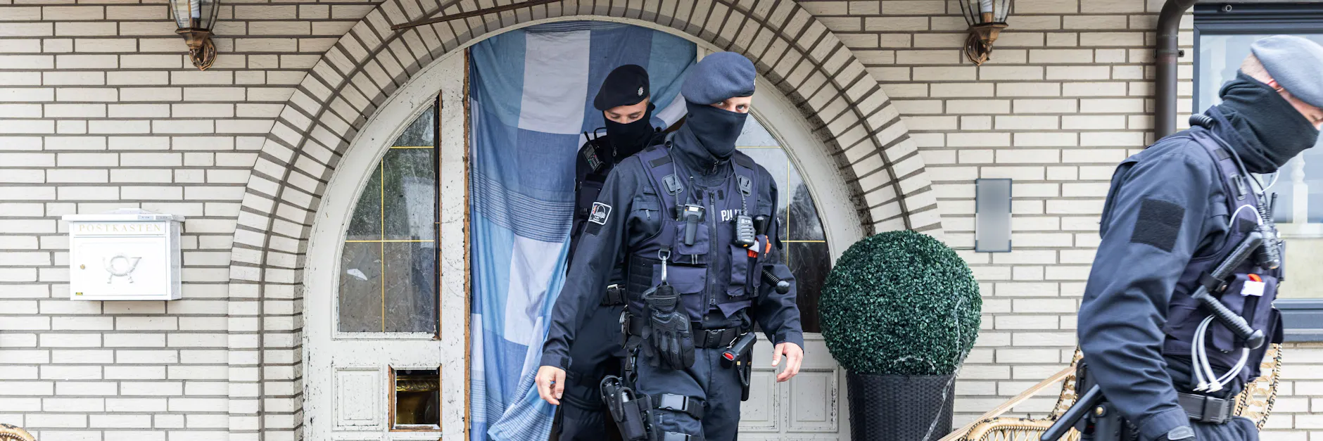 Polizisten verlassen eine Villa in Leverkusen. Zuvor hatten sie die Tür aufgesprengt und die Bewohner festgenommen.