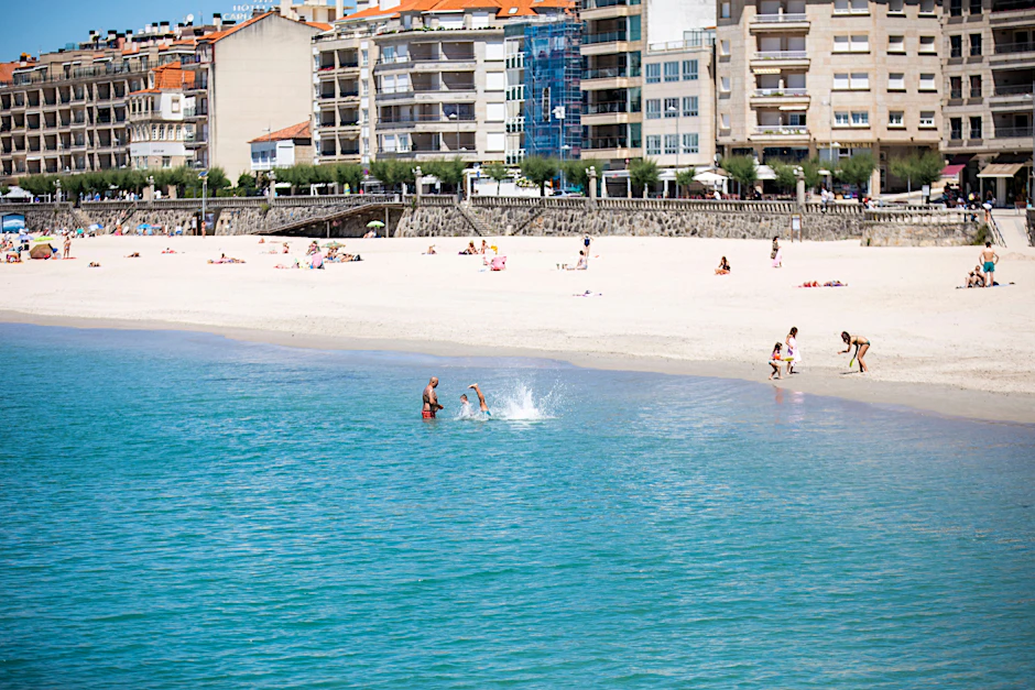 Strandbesucher baden bei schönem Wetter in Pontevedra, Spanien.