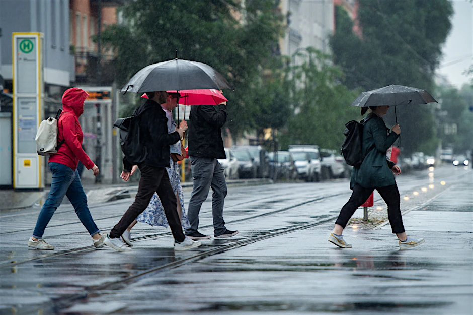 Berlin: Passanten schützen sich mit Regenschirmen vor den Wassermassen.