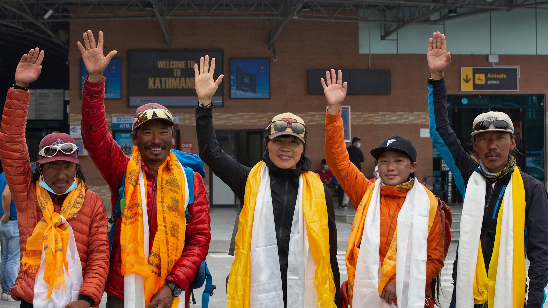 Bergsteigerin Tsang Yin-hung (Mitte) aus Hongkong winkt neben Pemba Dorje Sherpa (2. v. l.), Phurba Thiley Sherpa (l.), Nima Lhamu Sherpa (2. v. r.) und Phurba Tenjing Sherpa (r.) nach ihrem aufgestellten Rekord für den Aufstieg des Mount Everest den Journalisten am Flughafen zu. 