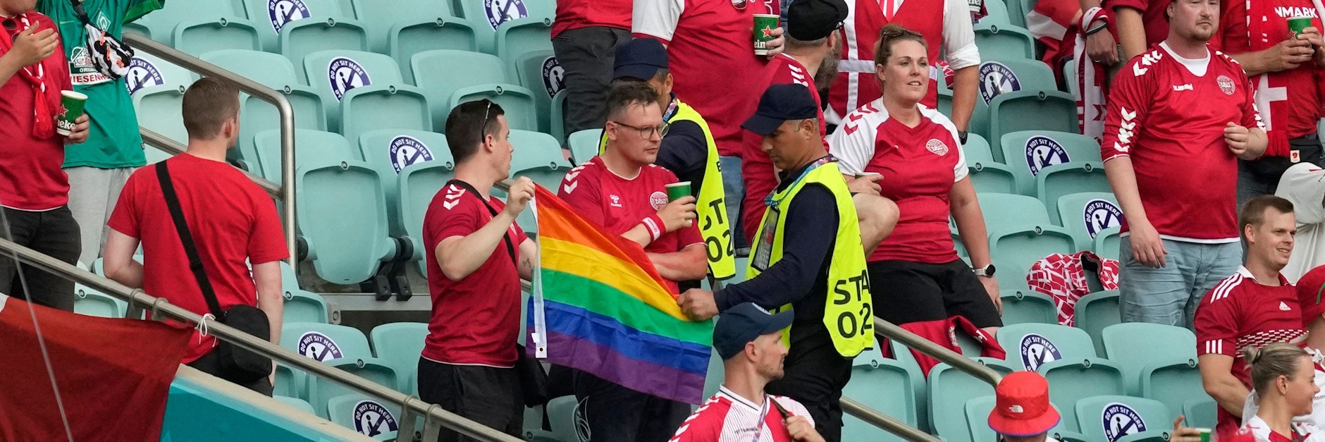 Ordner nehmen einem dänischen Fan seine Regenbogenflagge ab.