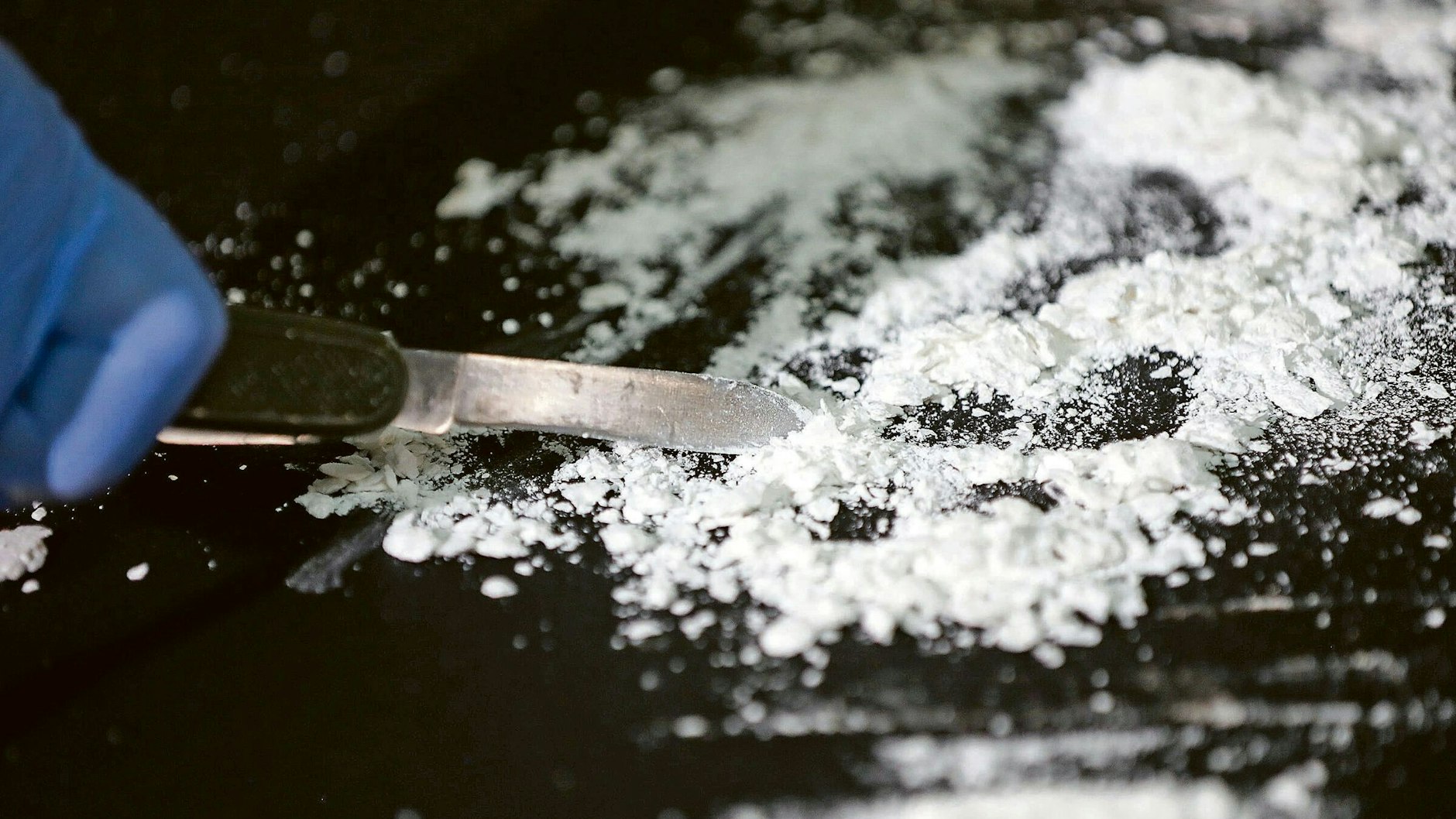 Ein Ermittler zerkleinert nach einem Drogenfund Kokain mit einem Messer (Symbolbild).&nbsp;