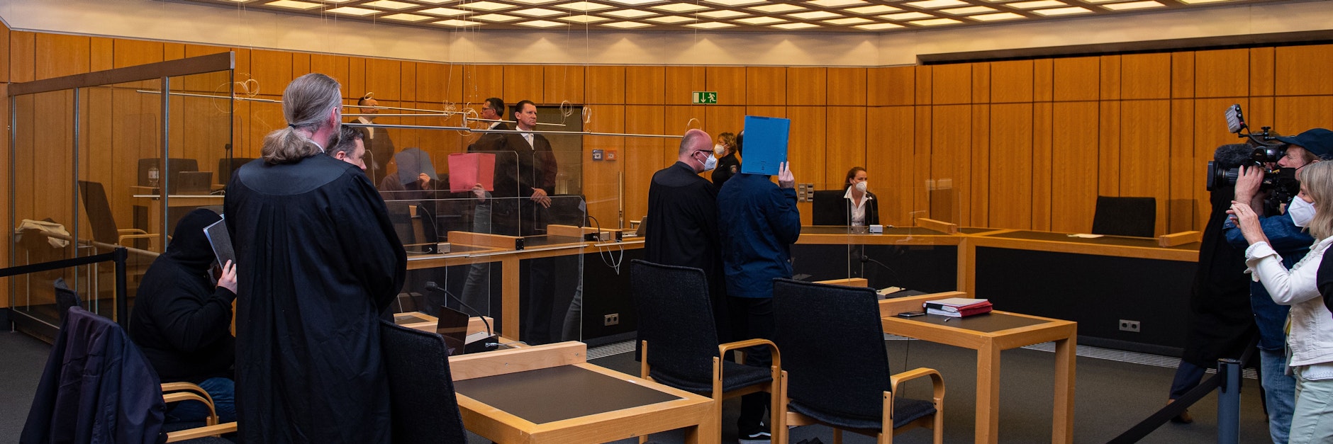 Blick in den Verhandlungssaal im Landgericht, die Angeklagten verdecken ihre Gesichter mit Aktenordnern. Im zentralen Prozess um den Missbrauchskomplex von Münster will das Gericht heute Urteile gegen fünf Angeklagte sprechen.