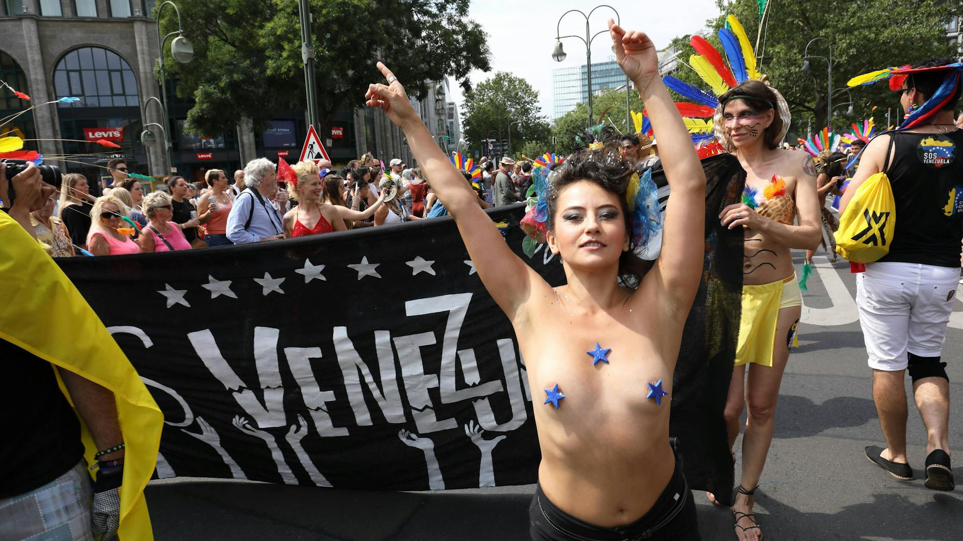 Eine Frau mit nacktem Oberkörper in Berlin, die ihre Nippel mit Sternchen abgedeckt hat. 