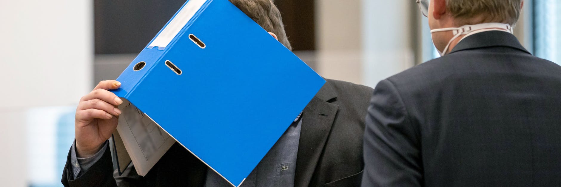 Der Angeklagte (mit dem Ordner im Gesicht) hat versucht, seine Frau mit einer vergifteten Zimtschnecke umzubringen.