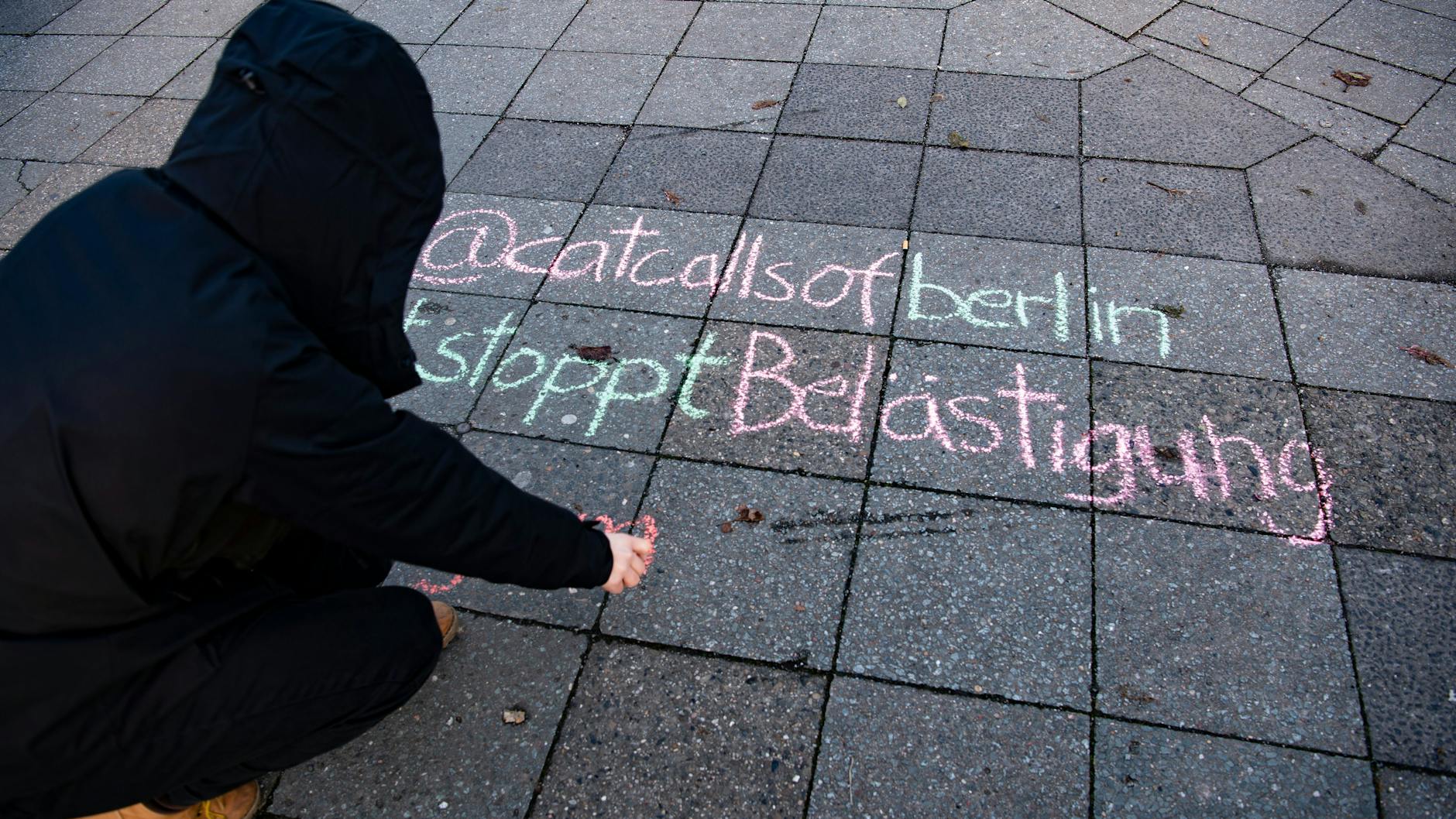 Studentin Lucie schreibt mit Kreide auf einen Bürgersteig. Ihre Initiative kämpft gegen „Catcalling“ – verbale und körperliche sexualisierte Belästigung auf der Straße.