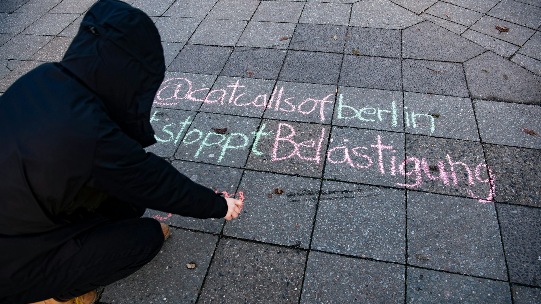 Studentin Lucie schreibt mit Kreide auf einen Bürgersteig. Ihre Initiative kämpft gegen „Catcalling“ – verbale und körperliche sexualisierte Belästigung auf der Straße.